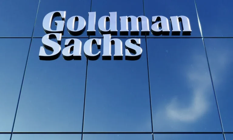 Goldman Sachs Logo an Glasfassade eines Bürogebäudes vor blauem Himmel