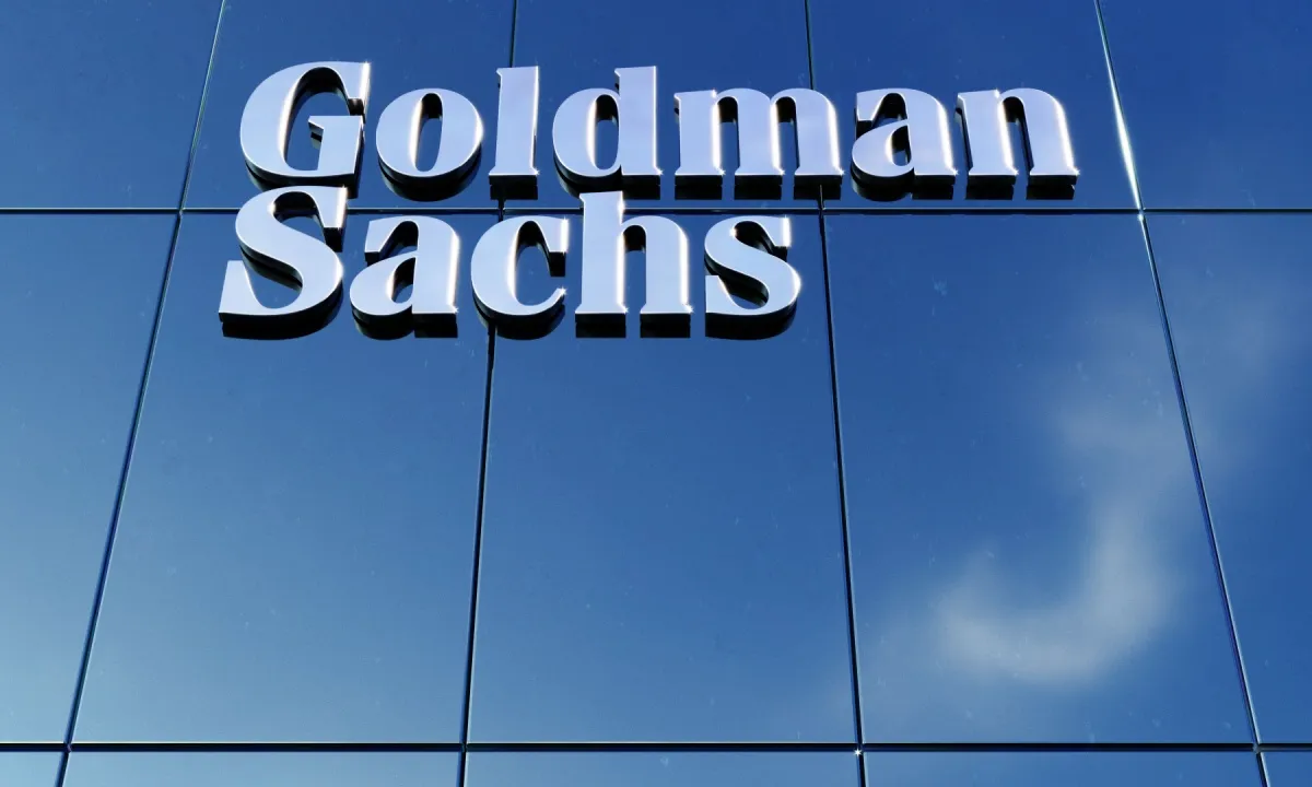 Goldman Sachs Logo an Glasfassade eines Bürogebäudes vor blauem Himmel